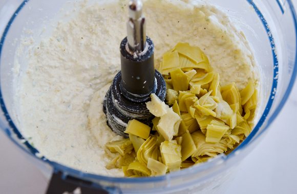 Food processor with creamy spread and diced artichokes