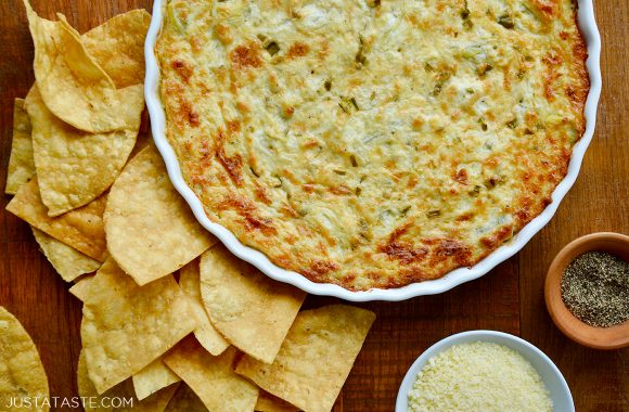 Easy, hot and creamy artichoke spread in baking dish surrounded by tortilla chips
