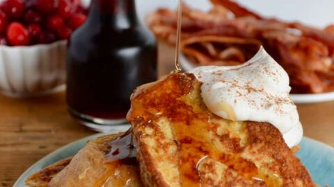 Maple syrup drizzled over Eggnog French Toast topped with whipped cream