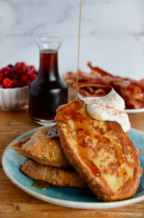 Maple syrup drizzled over Eggnog French Toast topped with whipped cream