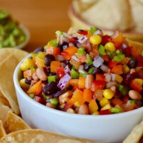 A white bowl with Texas Caviar and a white plate with tortilla chips