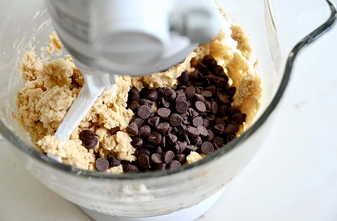 A bowl of a stand mixer with dough and chocolate chips