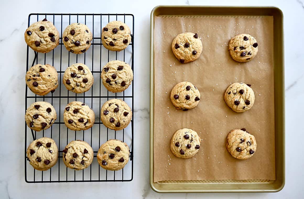 A top-down view of cookies cooling on a wire rack next to cookies on a parchment paper-lined baking sheet