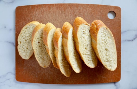 Sliced baguette on wood cutting board