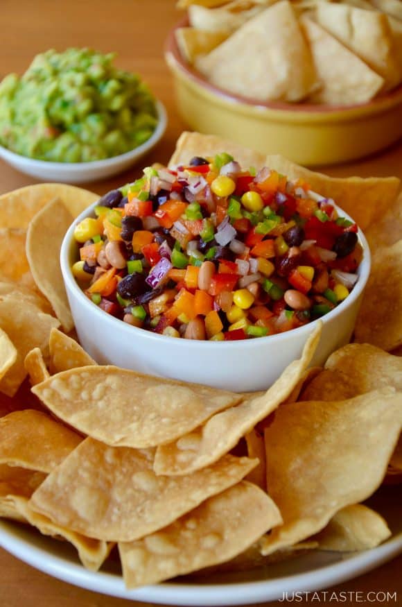 A white bowl with Texas Caviar on a plate containing tortilla chips