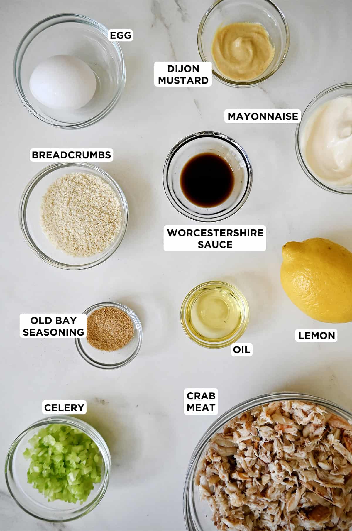 Ingredients to make crab cakes in various sizes of glass bowls.