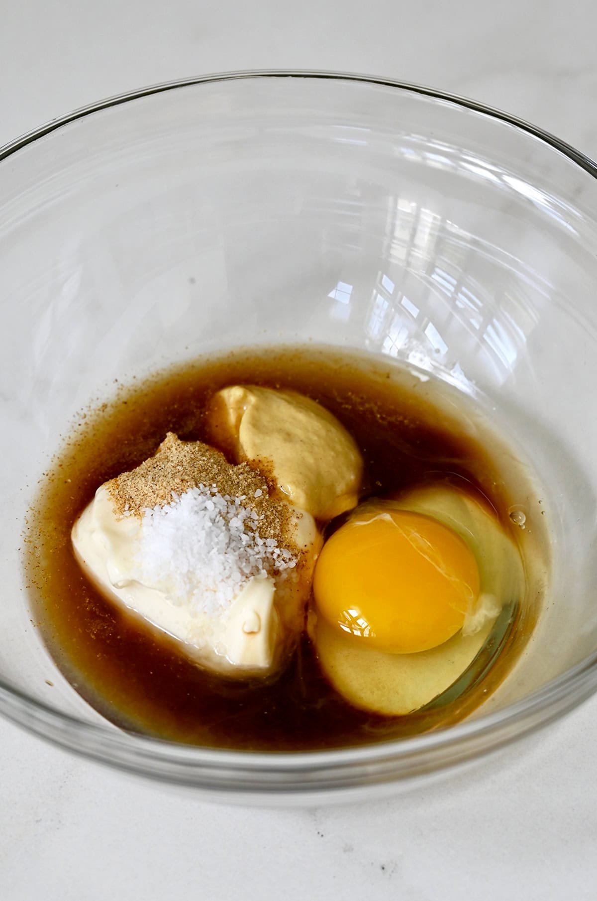 The flavorful base of crab cakes in a bowl: Worcestershire sauce, Dijon mustard, mayo, an egg and salt.