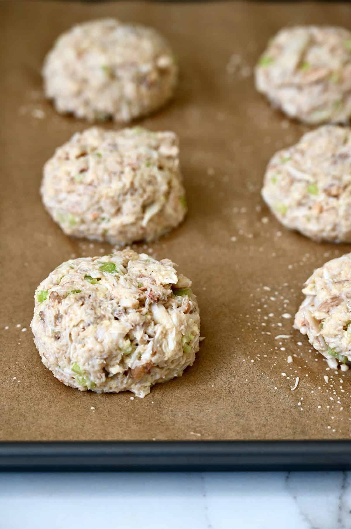 Shaped crab cakes on a parchment paper-lined tray before going into the refrigerator to chill.