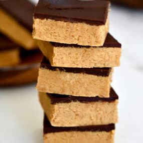 A tall stack of thick peanut butter bars with chocolate.