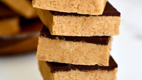 A tall stack of thick peanut butter bars with chocolate.