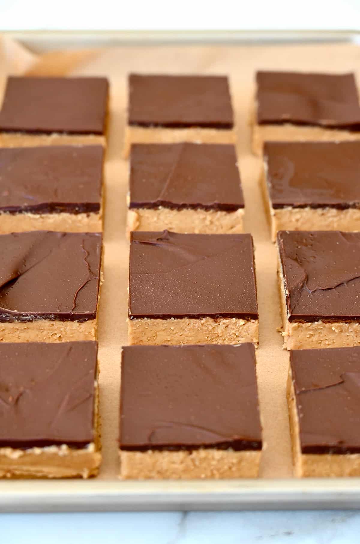Chocolate peanut butter bars sliced into perfect squares on a baking sheet.