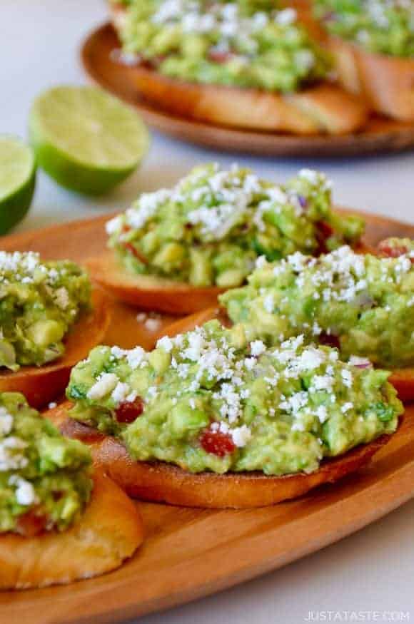 Guacamole bruschetta toasts on a wooden plate