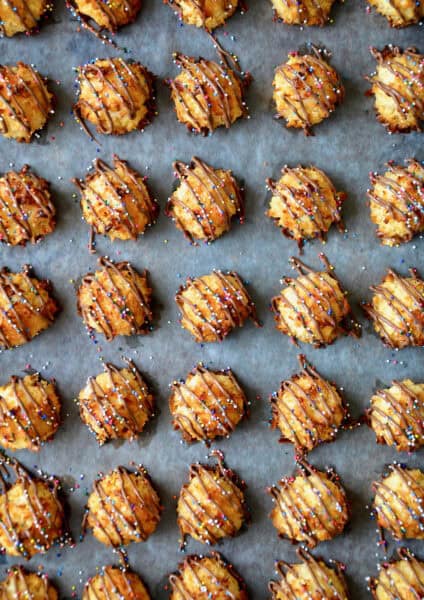 Perfect rows of coconut macaroons drizzled with melted chocolate and topped with rainbow sprinkles.