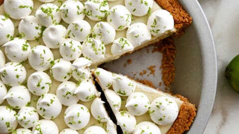 A top-down view of The Best Key Lime Pie in a pie plate topped with dollops of whipped cream