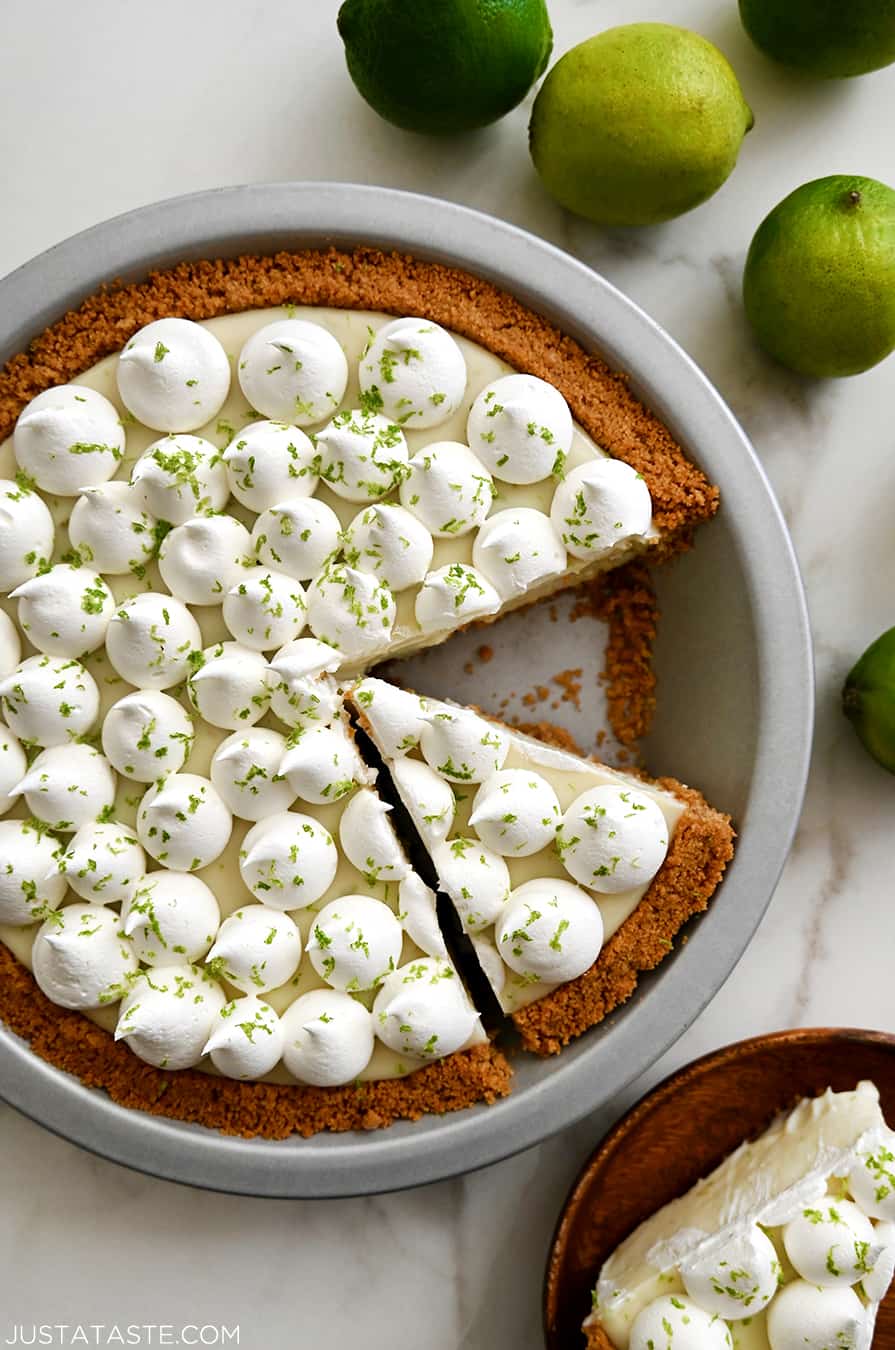 A top-down view of The Best Key Lime Pie in a pie plate topped with dollops of whipped cream