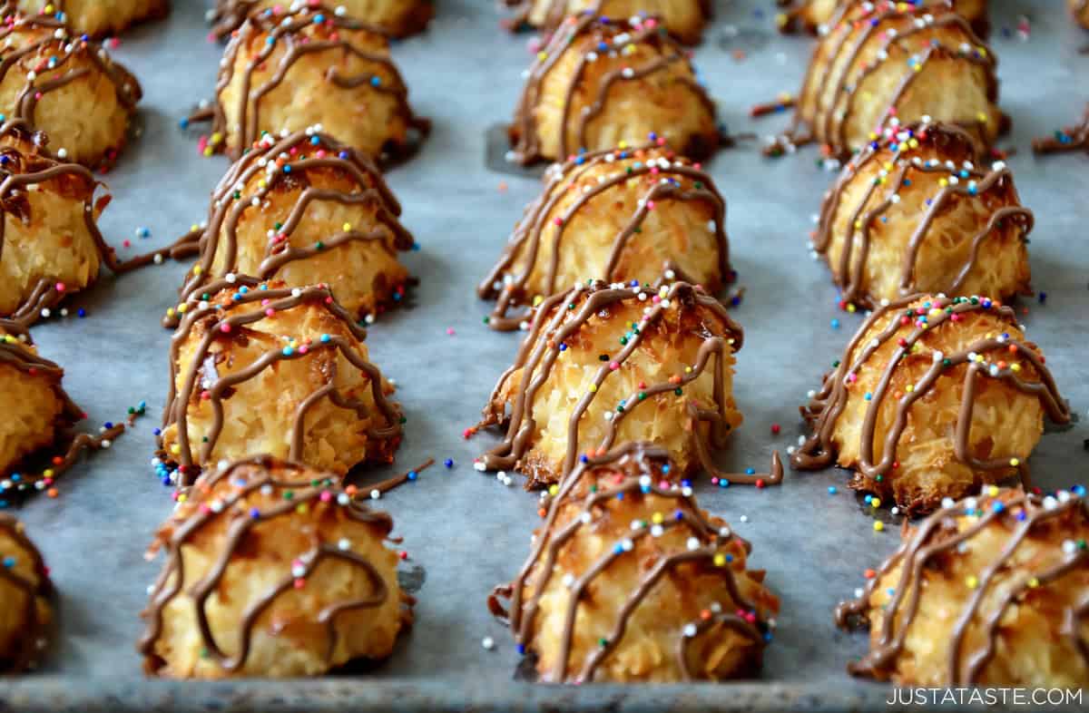 Chocolate drizzled coconut macaroons on a baking sheet.