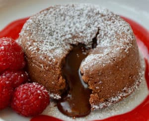 Chocolate Lava Cake on white plate with raspberry sauce and fresh raspberries