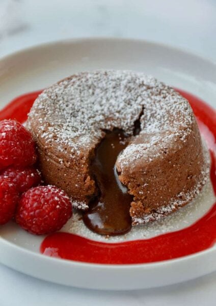 Chocolate Lava Cake on white plate with raspberry sauce and fresh raspberries
