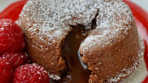 Chocolate Lava Cake on white plate with raspberry sauce and fresh raspberries