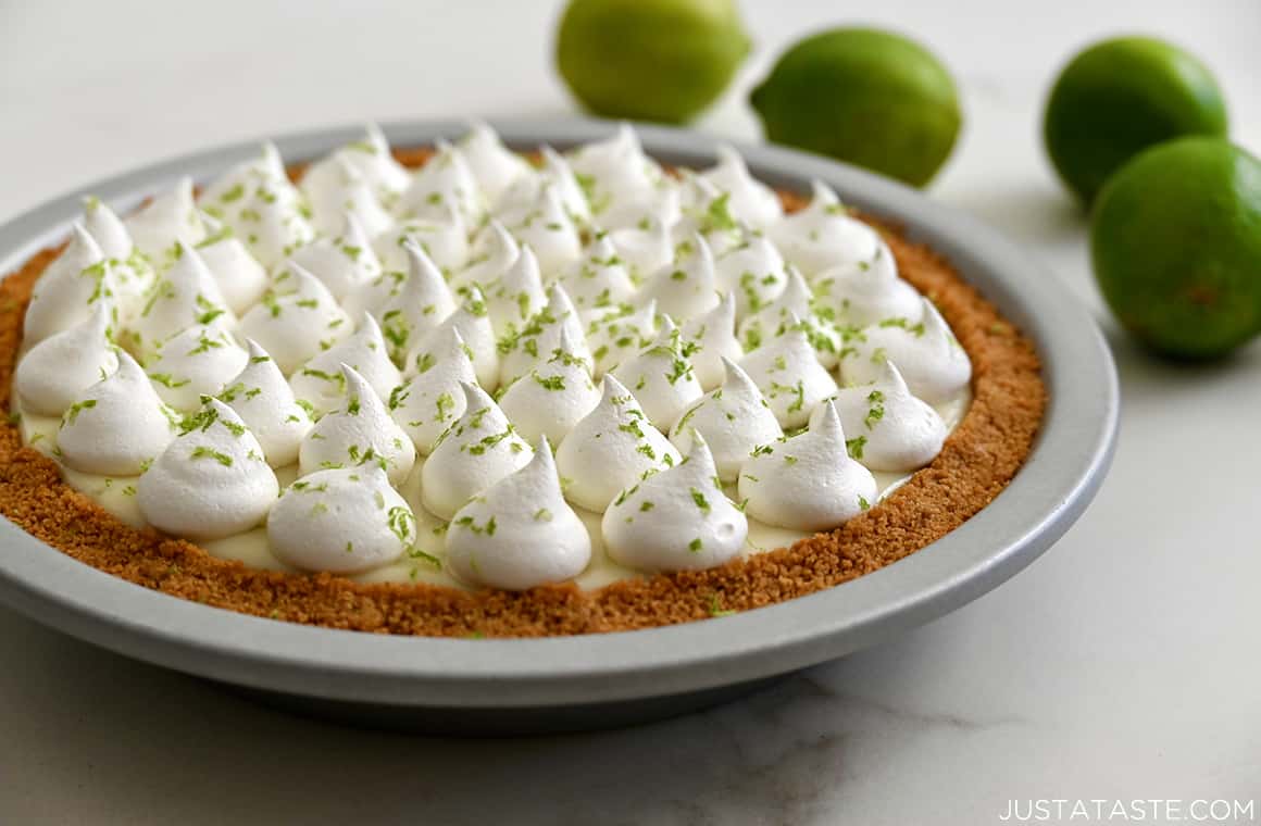 Easy key lime pie with a graham cracker crust and homemade whipped cream in a pie plate next to limes
