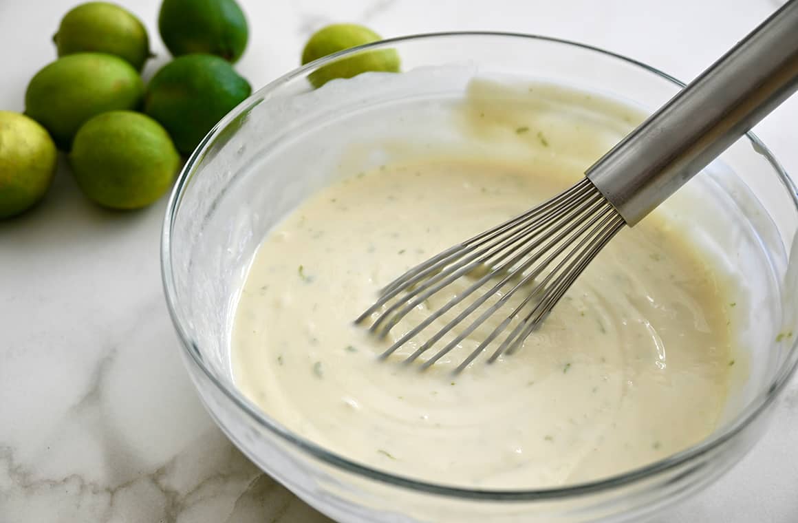 A clear bowl with a whisk and pie filling 