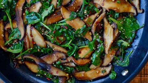 Skillet with sauteed mushrooms and spinach in a spicy garlic sauce