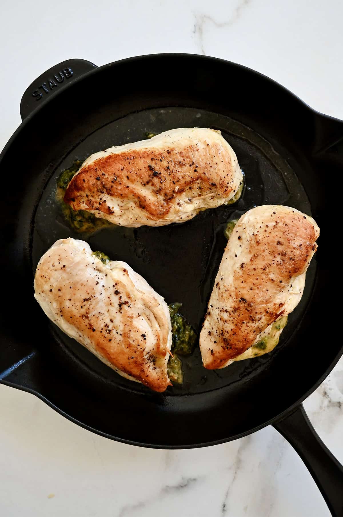 Seared stuffed chicken breasts in a cast iron skillet.