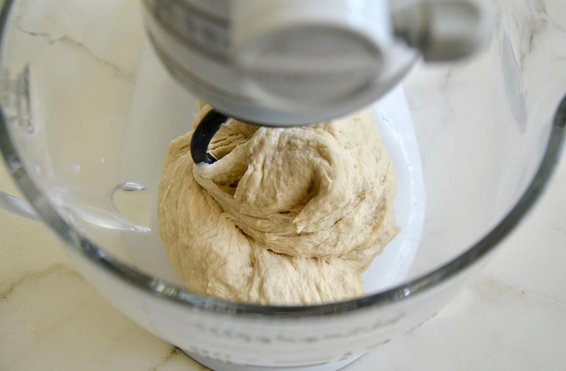 Pretzel dough in a stand mixer bowl with the hook attachment