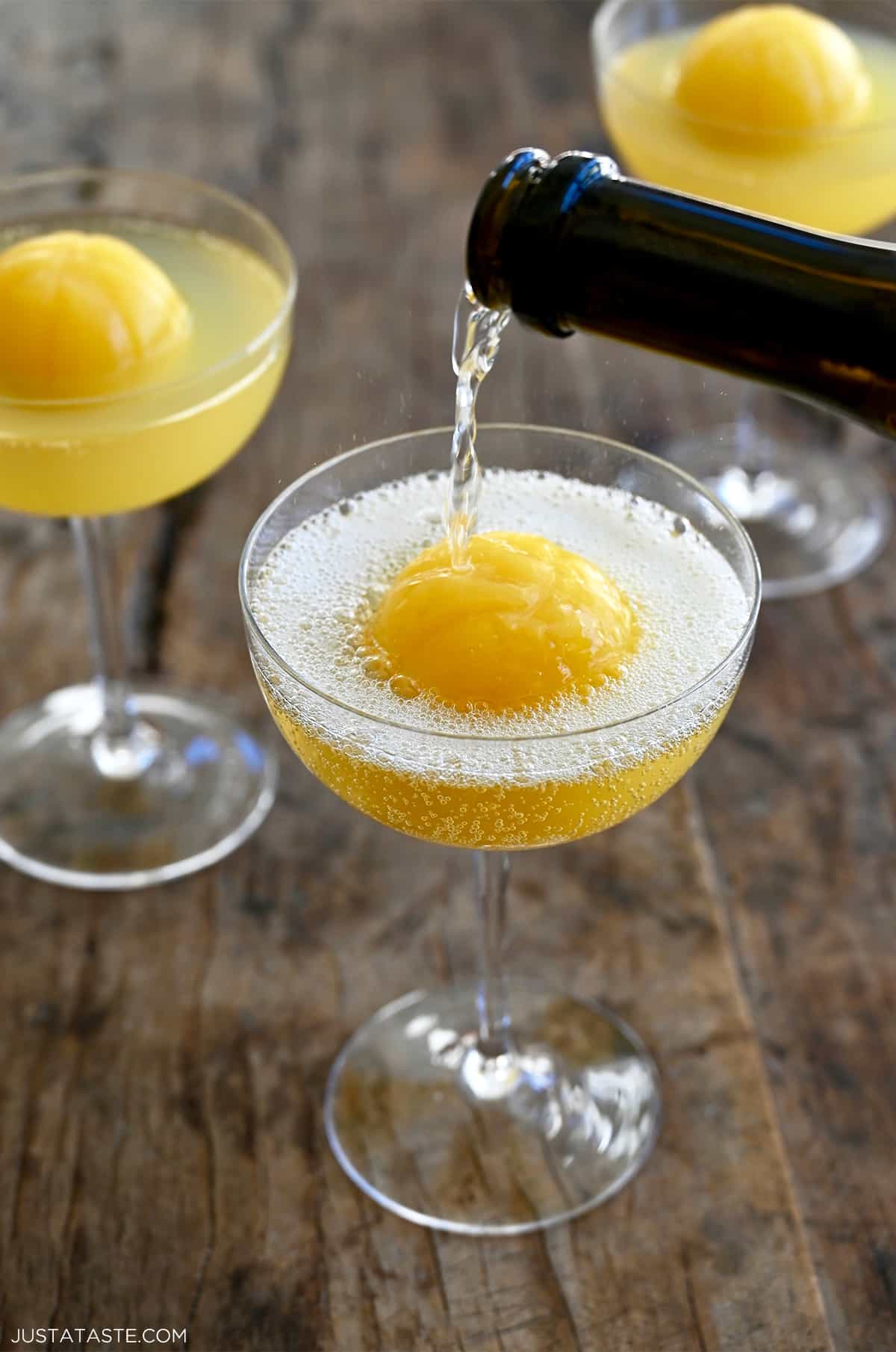 Champagne being poured over a basketball-shaped orange juice ice cube.