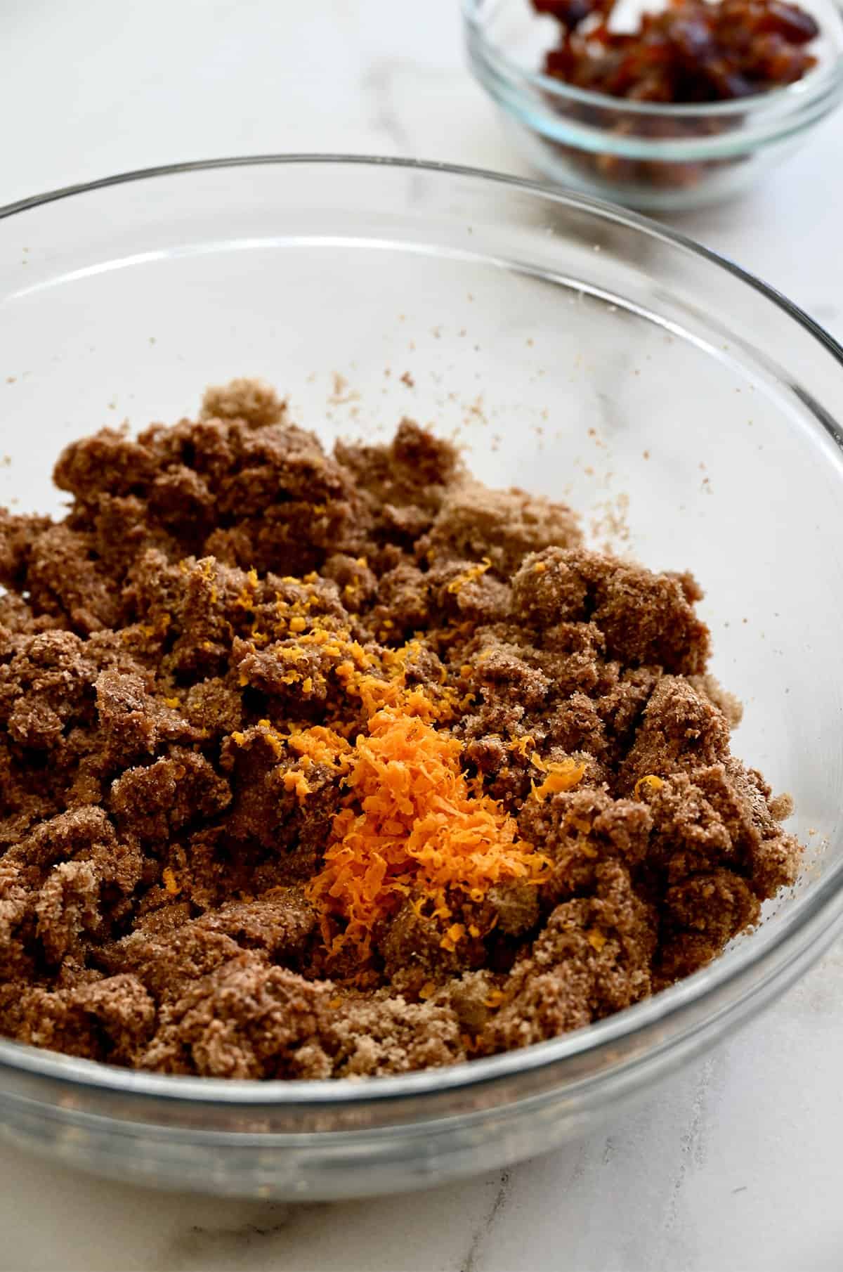 Orange zest atop bran muffin batter in a glass bowl.