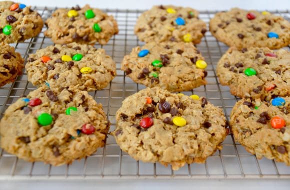 Freshly baked monster cookies cooling on wire rack