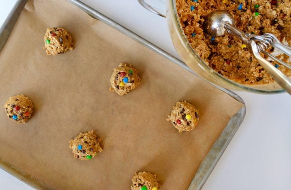 Unbaked cookies on baking sheet with cookie scoop