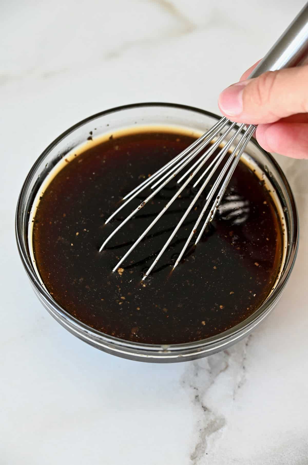 Black pepper sauce in a glass bowl with a whisk.