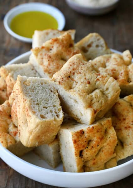 Slices of thick, Parmesan black pepper focaccia bread on a white serving plate.