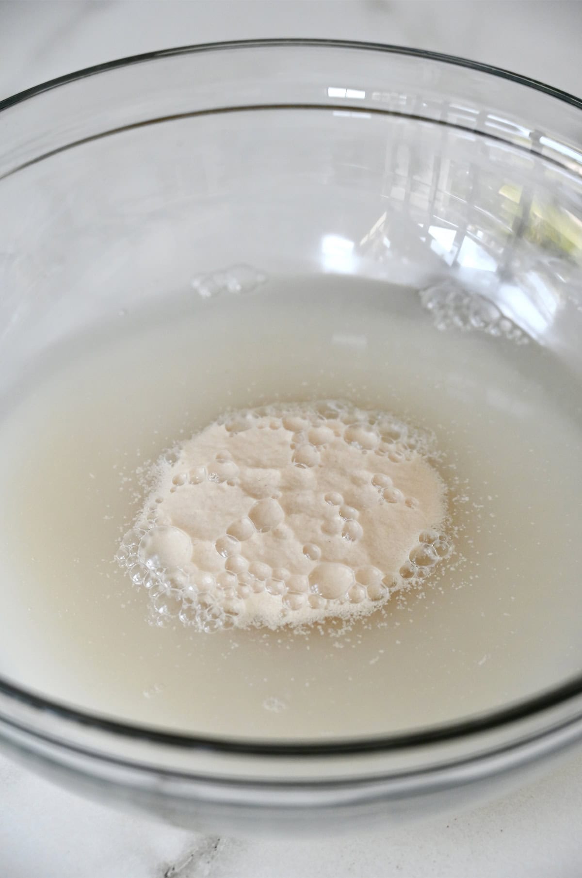 Frothy, activated yeast in water in a glass bowl.