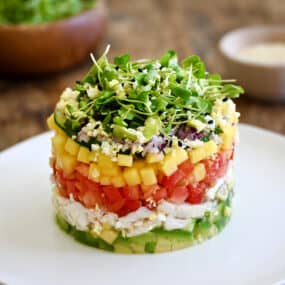 A crab stack with a layers of diced avocado, lump crab meat, diced tomato, diced mango, diced red onion and micro greens.