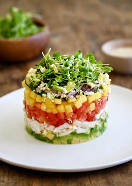 A crab stack with a layers of diced avocado, lump crab meat, diced tomato, diced mango, diced red onion and micro greens.
