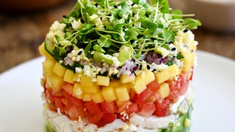 A crab stack with a layers of diced avocado, lump crab meat, diced tomato, diced mango, diced red onion and micro greens.