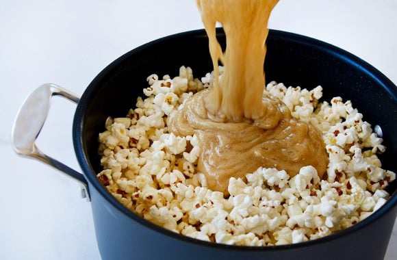 Caramel being poured over popcorn in stockpot