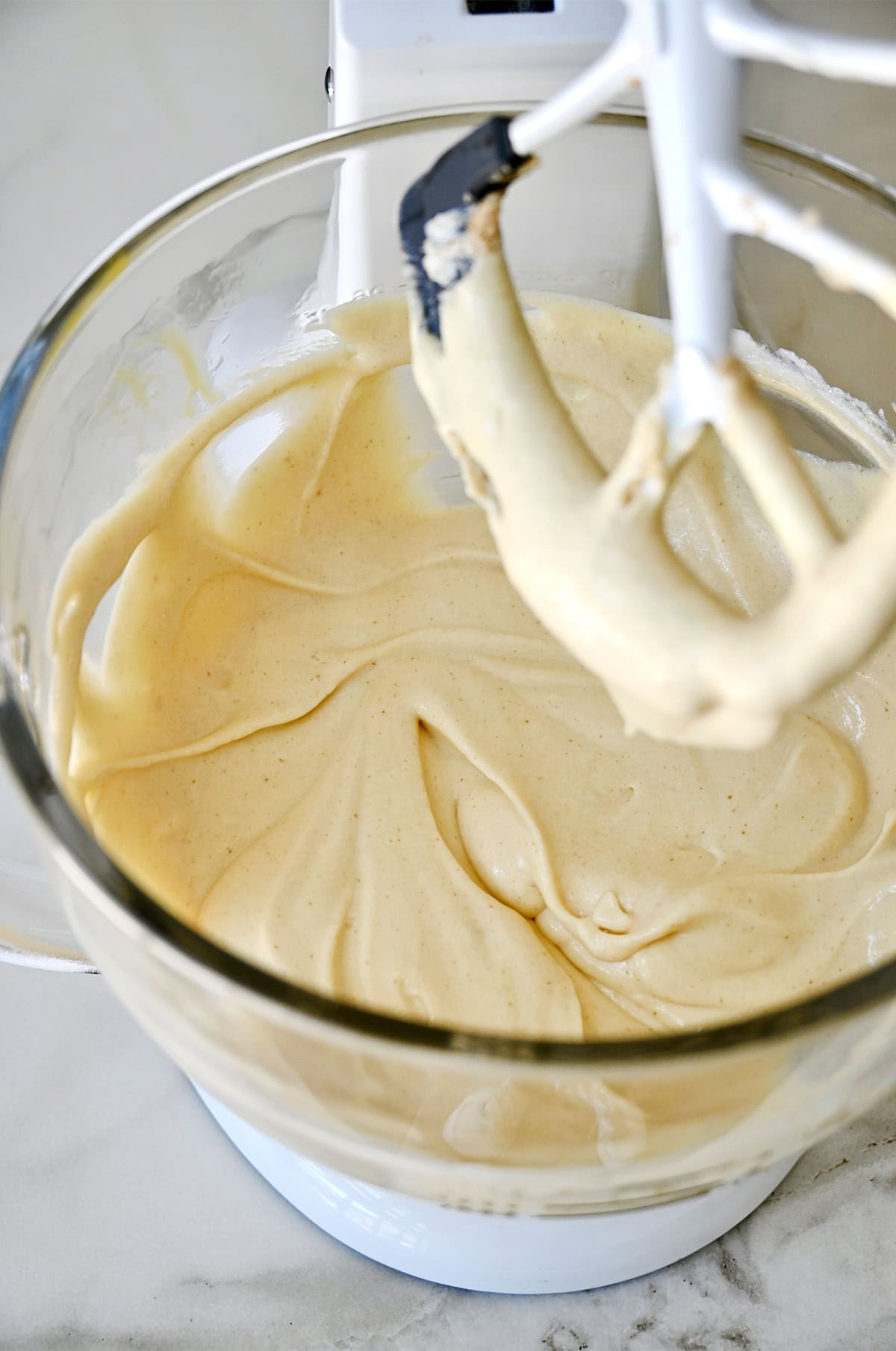 Vanilla cupcake batter in the bowl of a stand mixer with the paddle attachment.