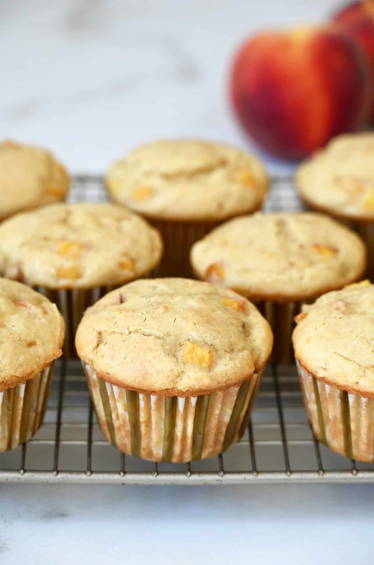 Freshly baked peach cupcakes cooling on a wire rack.