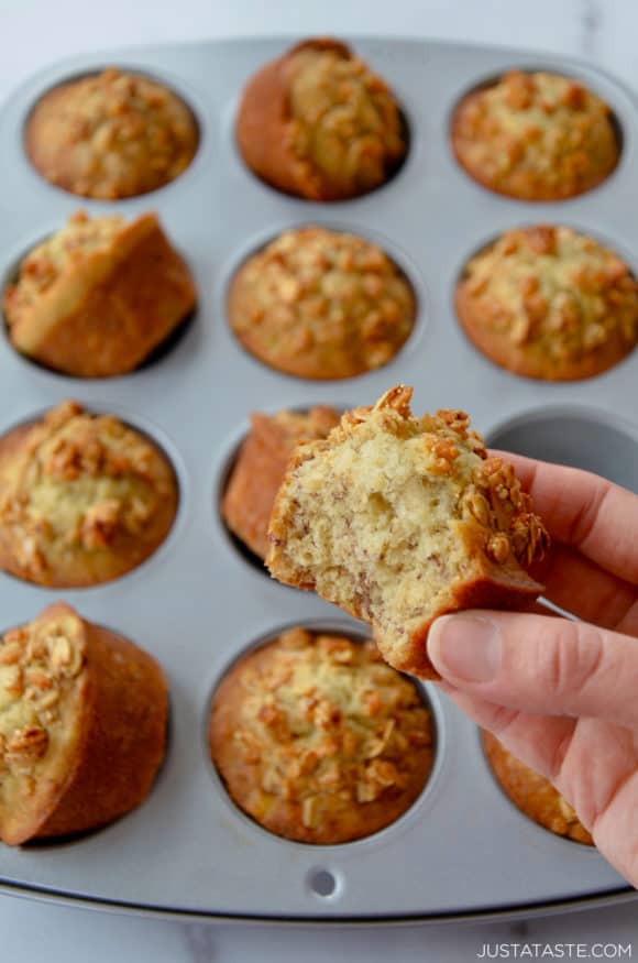 Hand holding banana muffin with bite taken out of it