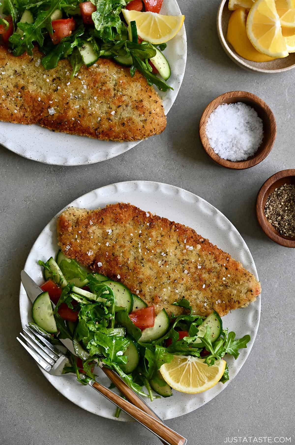 Crispy chicken schnitzel on a dinner plate with a side salad.
