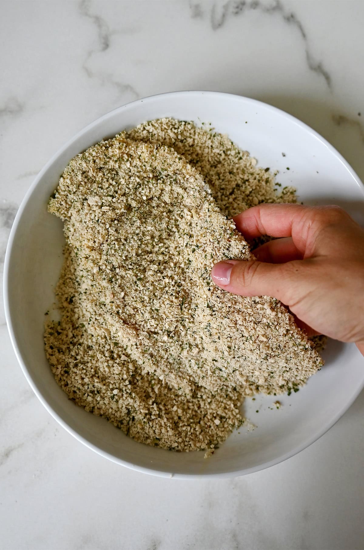 Final stage of breading schnitzel: dipping into breadcrumbs.
