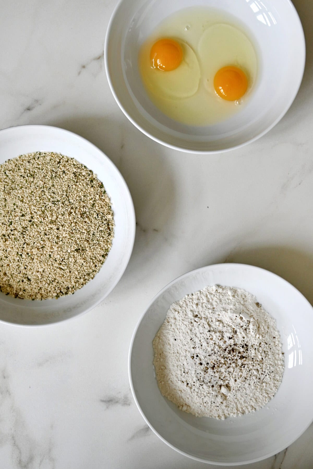 Standard breading station: Three bowls, each containing flour, whisked eggs and seasoned breadcrumbs.