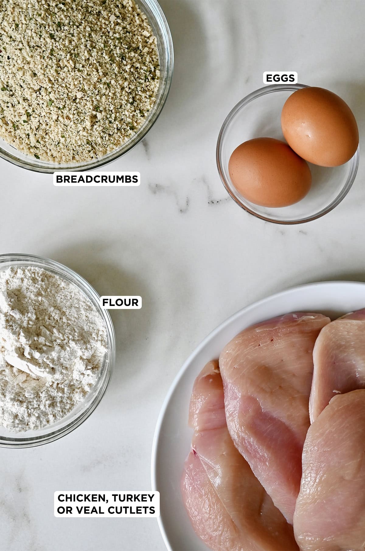Schnitzel ingredients: Boneless, skinless chicken breasts, flour, breadcrumbs, and two eggs.