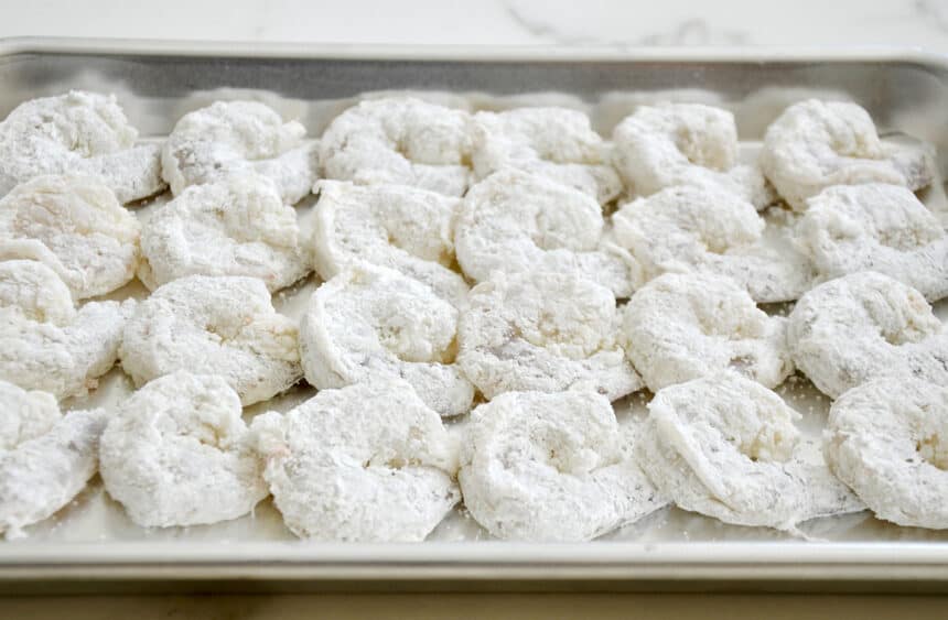 Shrimp covered in cornstarch on a baking sheet