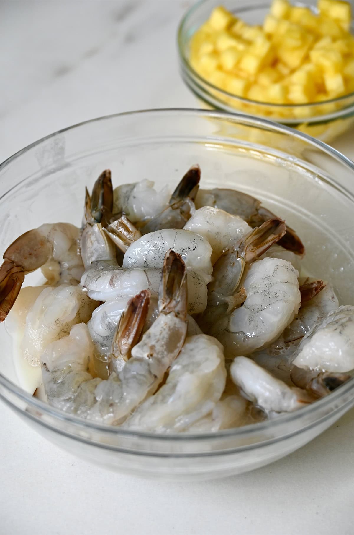Shrimp marinating in a glass bowl.
