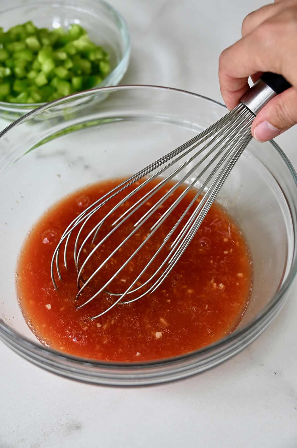 Sweet and sour stir-fry sauce in a bowl being whisked to combine.