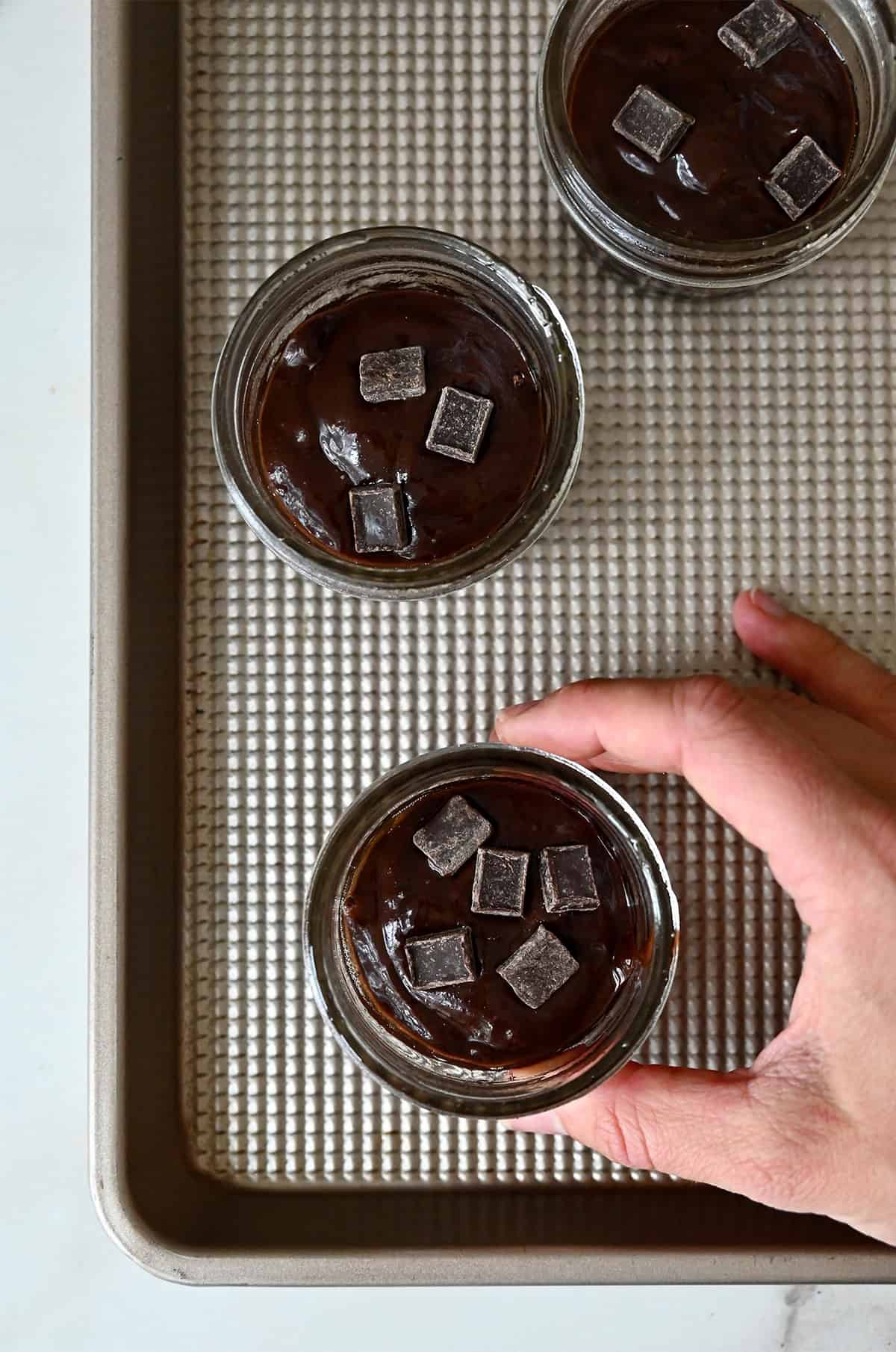 Unbaked brownies in small mason jars on a baking sheet.